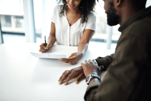two people sit at a table going over a from that discusses insurances accepted