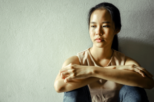 a young woman sits on the ground and leans against a wall struggling with understanding the myths and facts of cocaine use